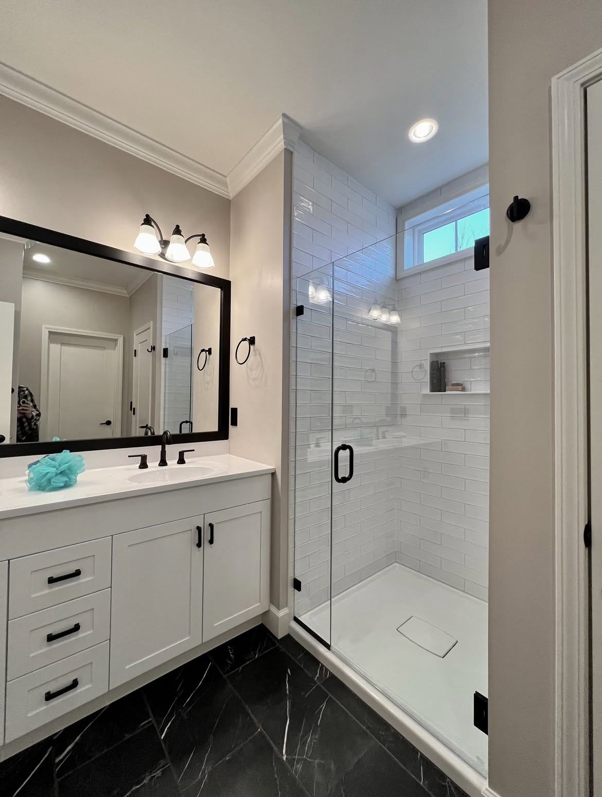 Bathroom with white vanity, black mirror and fixtures, and a glass walk-in shower