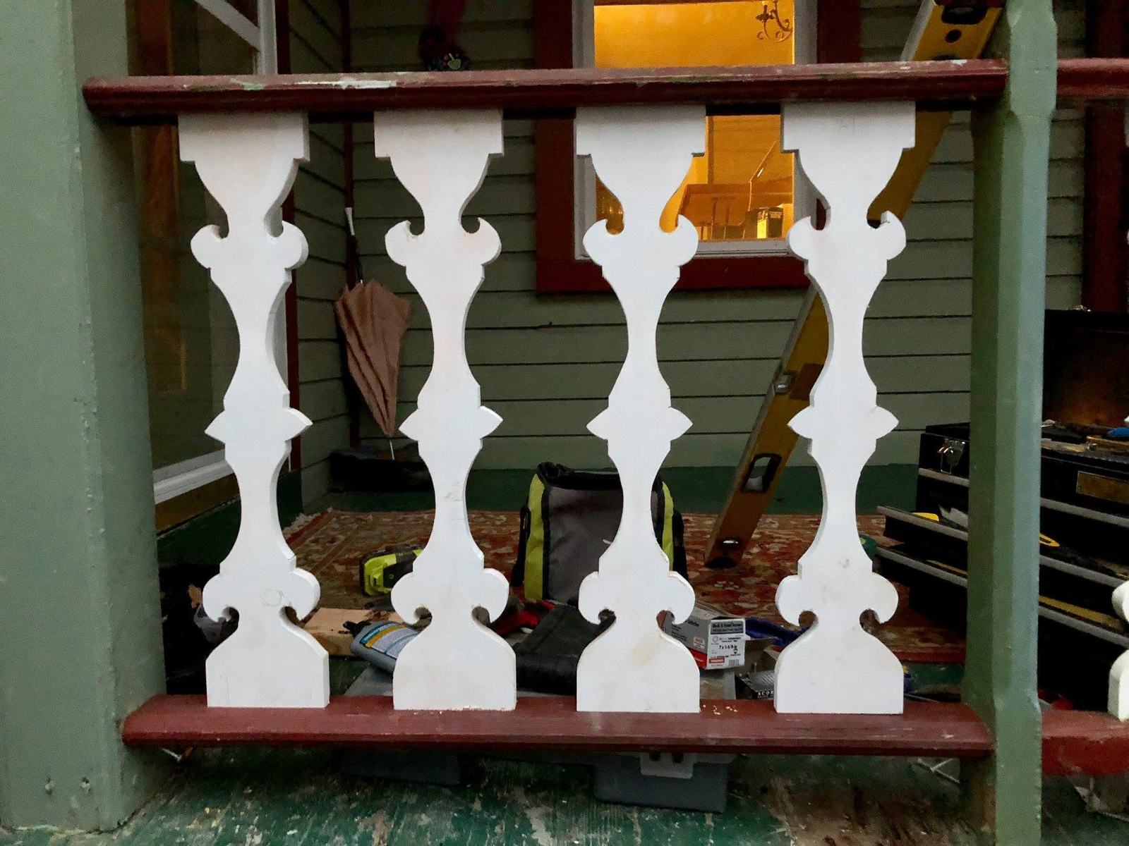 White scroll-cut balusters on a green porch rail