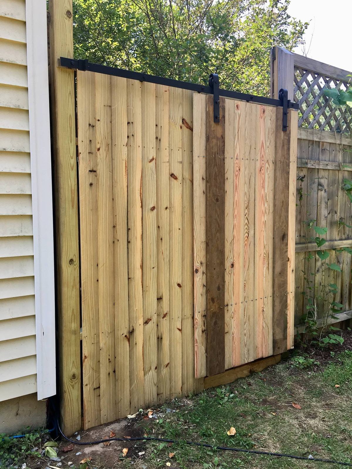 Wood outdoor shower enclosure with a sliding barn door