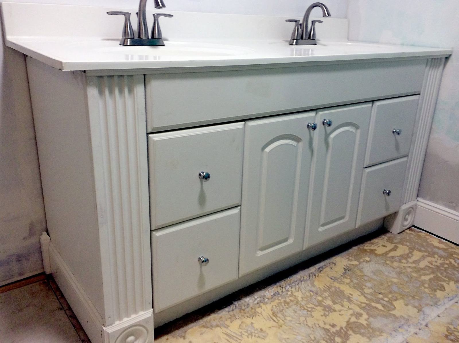 White vanity with fluted trim and two faucets