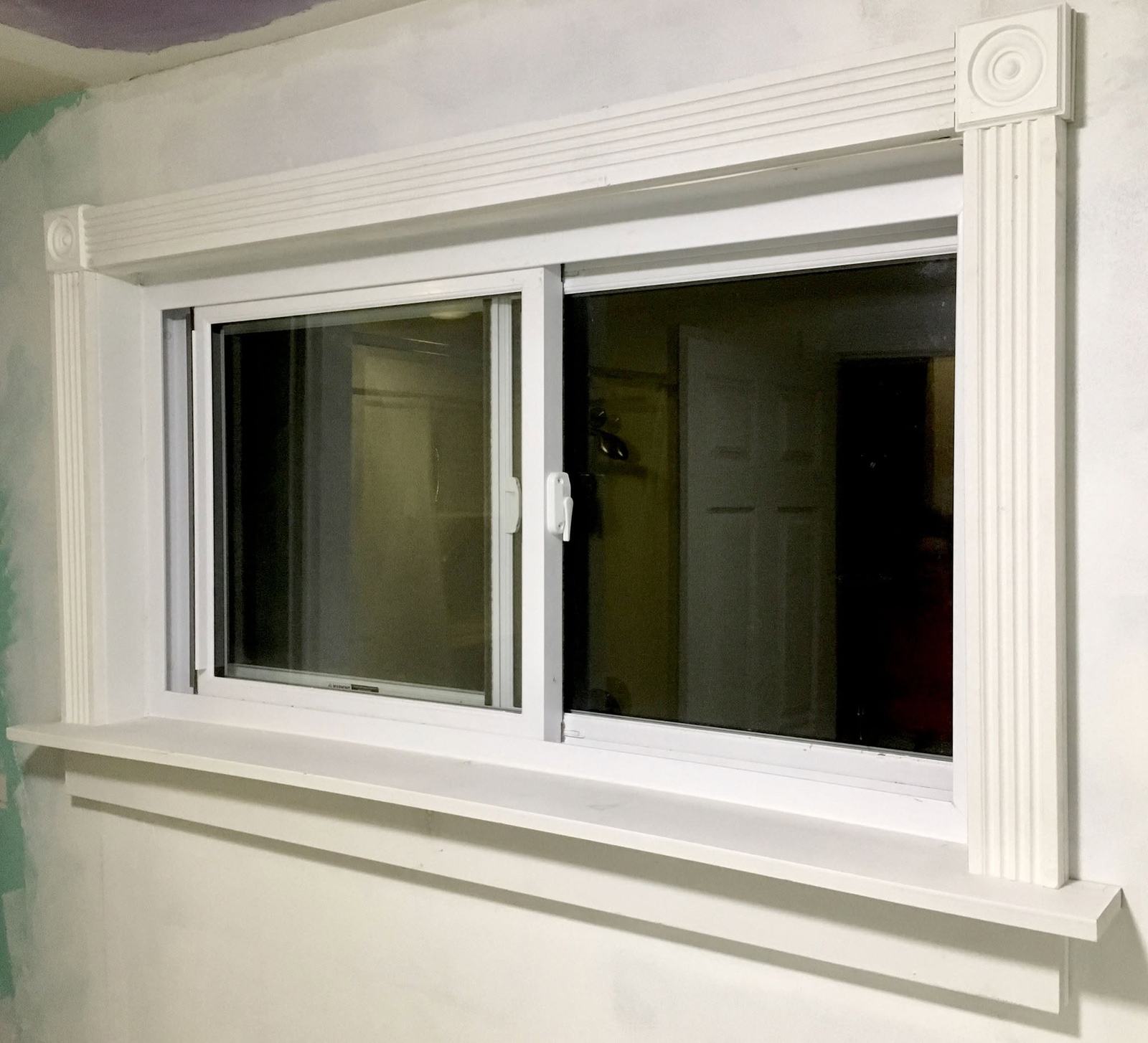 Window cased in white trim with corner rosettes